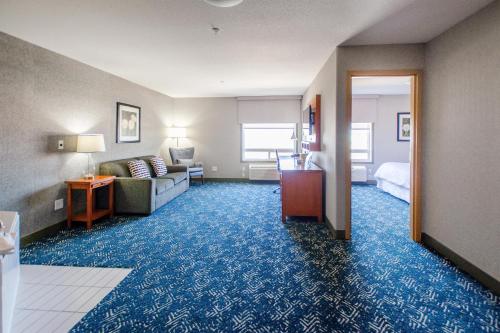 Habitación de hotel con cama y sala de estar. en Four Points by Sheraton Saskatoon en Saskatoon