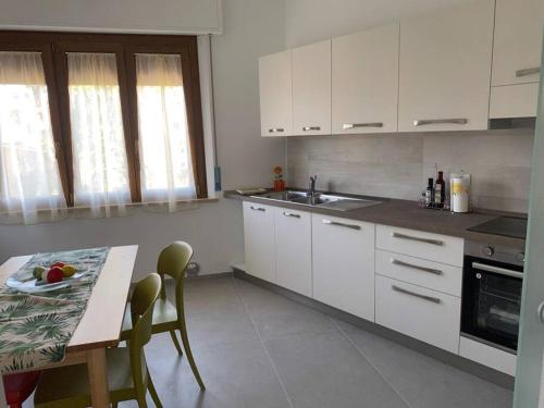 una cocina con armarios blancos y una mesa con un plato. en Sopra la Posta, en Monteriggioni