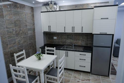 Fishta apartments Q5 35 في فيليبوجي: مطبخ بدولاب بيضاء وطاولة وكراسي بيضاء