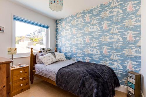 a bedroom with a bed with a blue and white wallpaper at Gulland in Port Isaac