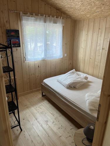 une chambre avec un lit dans une pièce avec une fenêtre dans l'établissement Maison bois dans la forêt de Carcans-plage, à Carcans