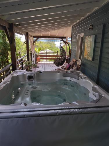 eine Whirlpool-Badewanne auf der Veranda eines Hauses in der Unterkunft LES GÎTES DU DOMAINE DE PETITE-ANSE in Bouillante