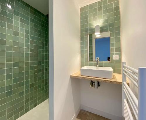 une salle de bain carrelée verte avec un lavabo et un miroir dans l'établissement Le Logis des Templiers Vieux Port, à La Rochelle