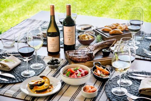 a table with wine bottles and food and wine glasses at Posada Salentein in Los Árboles