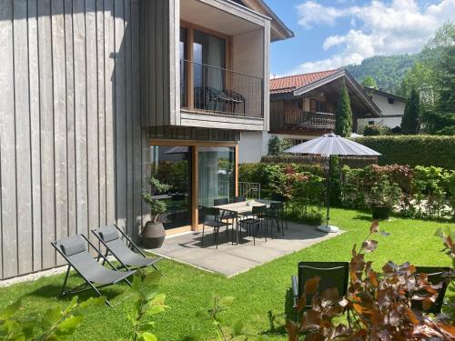 een achtertuin met een tafel en stoelen en een parasol bij Traumferienhaus 1 mit Sauna und Bergblick in Garmisch-Partenkirchen