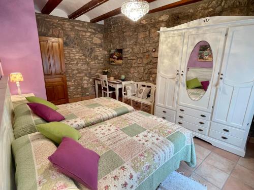 sypialnia z 2 łóżkami w pokoju z kamienną ścianą w obiekcie Casa Tío Romana Somhome w mieście Santa Magdalena de Pulpis