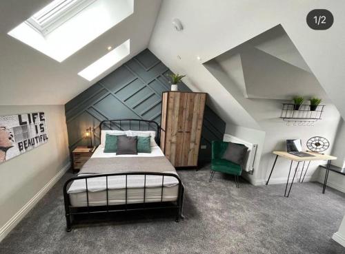 a attic bedroom with a bed and a green chair at Mansel House - Sleeps 14 - By TIFA Stays in Swansea