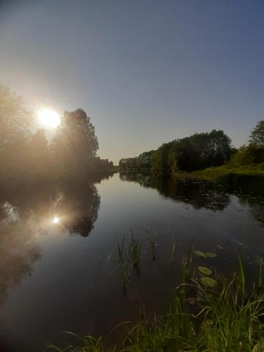 a river with the sun reflecting in the water at Krastmslas in Smaltāni