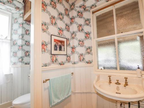 a bathroom with a sink and floral wallpaper at Druidaig Lodge in Dornie