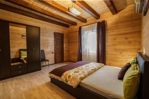 ein Schlafzimmer mit einem Bett in einem Zimmer mit Holzwänden in der Unterkunft Dacha 9 in Voropayev