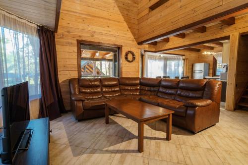 a living room with a leather couch and a table at Dacha 9 in Voropayev