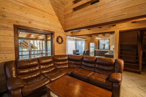 a living room with a leather couch in a cabin at Dacha 9 in Voropayev