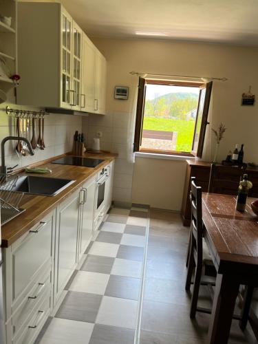 Baške Oštarije的住宿－Mountain House Paula，厨房配有白色橱柜、桌子和窗户。