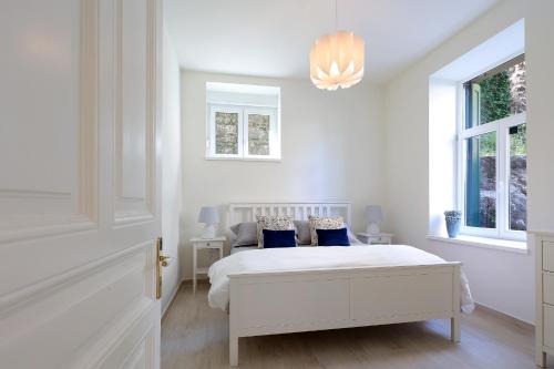 biała sypialnia z łóżkiem i 2 oknami w obiekcie Apartment with patio 50m from the beach and Lungomare w mieście Opatija