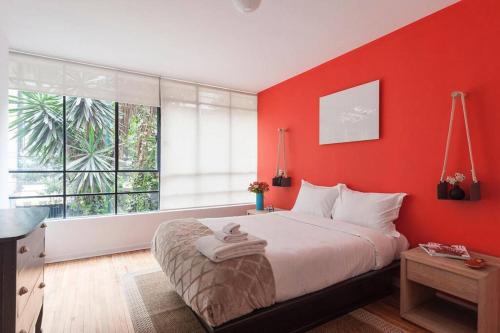 a red bedroom with a bed and a large window at Henry Ibsen By MrW in Mexico City
