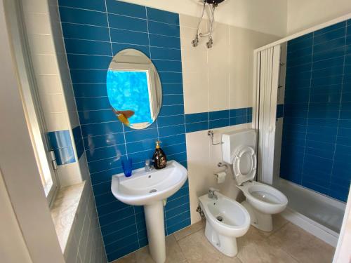 a blue tiled bathroom with a sink and a toilet at Lu Jentu in Torre Ovo