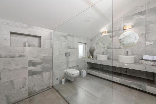 uma casa de banho com 2 lavatórios, um WC e 2 espelhos em Luxury Vila Divina-Exceptional privacy em Mlini