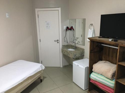una camera con letto, televisore e lavandino di BIG HOTEL a Osório