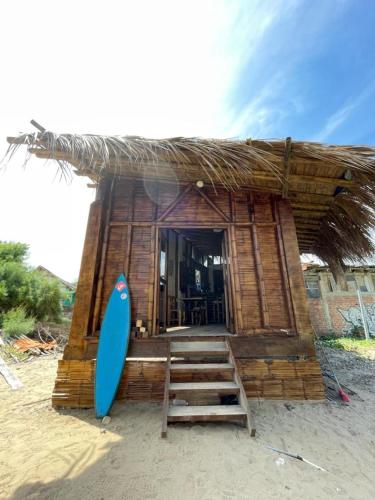 una pequeña choza con una tabla de surf delante de ella en Mancora Sunset House, en Máncora