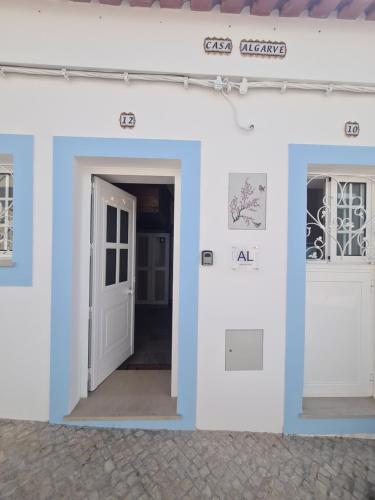 een wit gebouw met een deur en twee ramen bij Casa Tradicional Algarvia in Lagoa