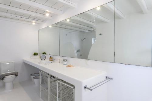 een witte badkamer met een wastafel en een spiegel bij Salty Blè in Agios Ioannis Mykonos