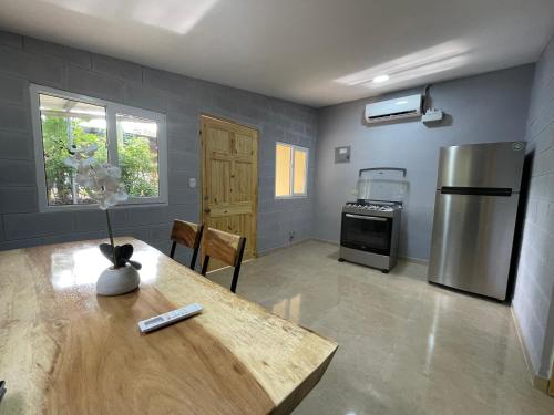 a kitchen with a table and a stainless steel refrigerator at Hostal Camila’s in Tamanique