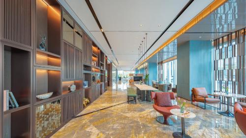 a lobby of a building with chairs and tables at Holiday Inn Changchun Oriental Plaza by IHG in Changchun