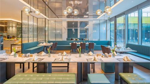 a restaurant with tables and chairs and windows at Holiday Inn Changchun Oriental Plaza by IHG in Changchun