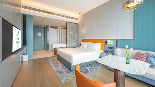 a hotel room with a bed and a tv and a couch at Holiday Inn Changchun Oriental Plaza by IHG in Changchun