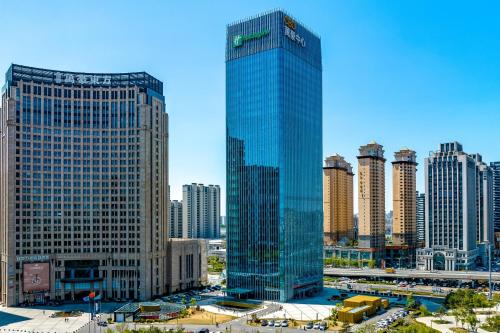 a tall glass building in the middle of a city at Holiday Inn Changchun Oriental Plaza by IHG in Changchun