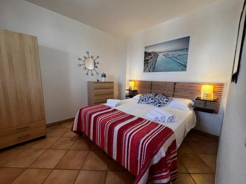 a bedroom with a bed with a red and white blanket at ONDA BLU-Appartamenti in Torre dell'Orso