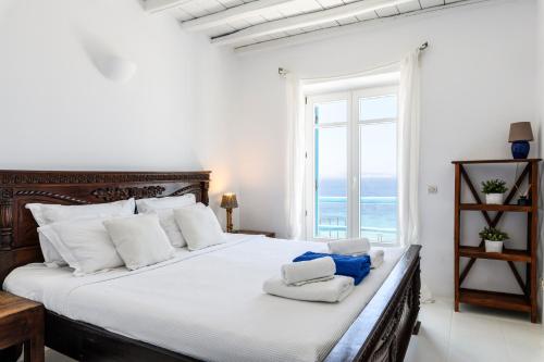a bedroom with a bed with white pillows and a window at Salty Blè in Agios Ioannis Mykonos
