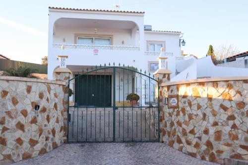 a white house with a gate and a stone wall at Luxury Villa with ocean view in Luz
