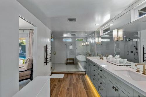 a white bathroom with two sinks and a shower at Lola Vista in Palm Springs