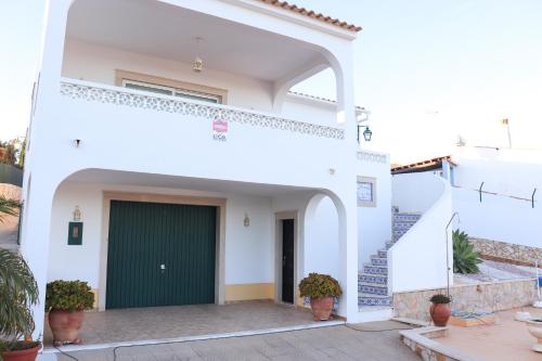 ein weißes Haus mit einer grünen Tür und einer Treppe in der Unterkunft Luxury Villa with ocean view in Luz