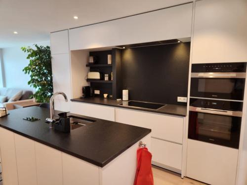 uma cozinha com armários brancos e um balcão preto em Appart Noah SeaFront em Knokke-Heist