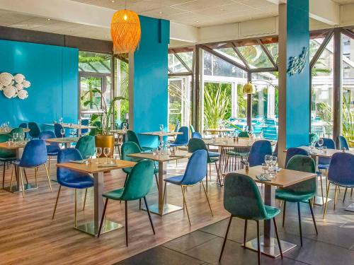un restaurante con paredes azules, mesas y sillas en Novotel Marseille Est Porte d'Aubagne en Marsella