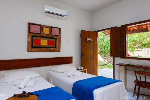 a bedroom with two beds and a window at Pousada Estalagem Vila Tania in Itaúnas