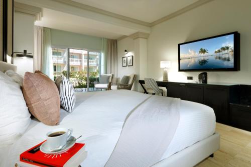 a hotel room with a white bed and a tv at Grand Palladium Jamaica Resort & Spa All Inclusive in Lucea