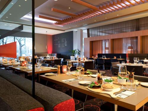 een restaurant met houten tafels en stoelen en een eettafel bij Novotel Amsterdam City in Amsterdam