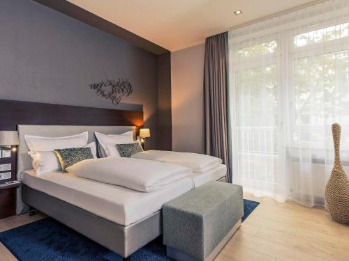 a bedroom with a large bed and a large window at Mercure Hotel Koeln Belfortstrasse in Cologne