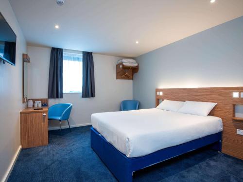 um quarto de hotel com uma cama, uma secretária e uma cadeira em ibis budget London Bromley Town Centre em Bromley