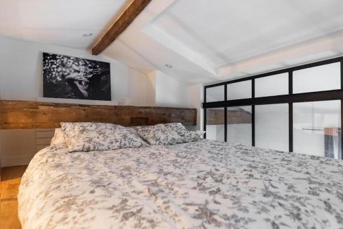 ein Schlafzimmer mit einem großen Bett und einem großen Fenster in der Unterkunft Appartement type loft - 40m² Marais in Paris