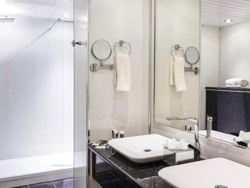 een witte badkamer met een wastafel en een douche bij Mercure St Helens in Saint Helens
