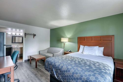 een hotelkamer met een bed en een stoel bij Suburban Studios Neenah in Neenah