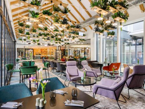 un restaurante con mesas, sillas y plantas en Mercure Tokaj Center, en Tokaj