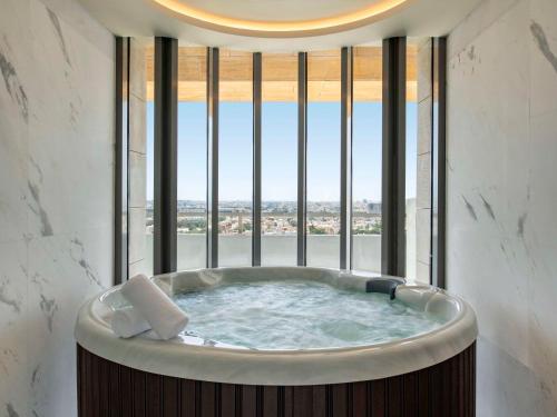 Swissotel Living Jeddah في جدة: حوض استحمام في غرفة مع نافذة كبيرة