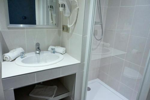 a white bathroom with a sink and a shower at Hotel de la Couronne in Aix-les-Bains