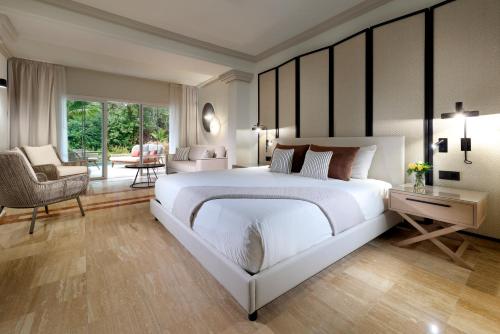 a bedroom with a large white bed and a living room at Grand Palladium Jamaica Resort & Spa All Inclusive in Lucea
