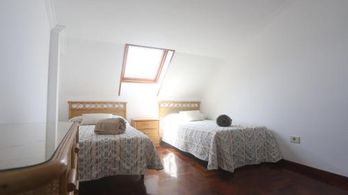 a bedroom with two beds and a window at Ático Laxe Grande in A Guarda